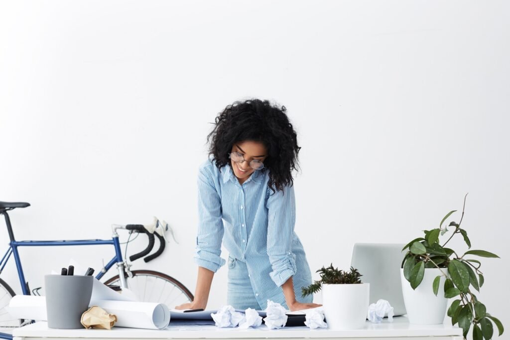 Femme au bureau debout regardant ses plans sur la tête penchée vers le bas